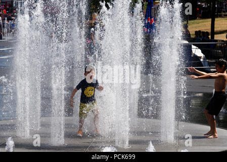 Los niños refrescarse jugando en fuentes de agua en Rue Jeanne Mance en Montreals distrito de entretenimiento. Tomadas durante la ola de calor de 2108. Foto de stock