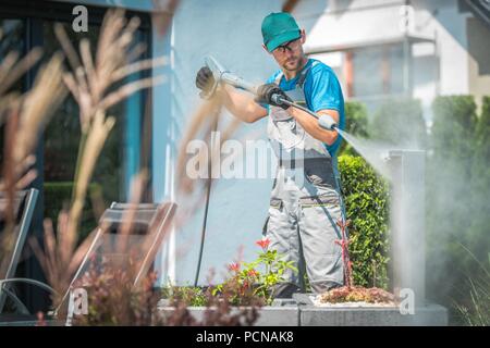 Lavado a presión en el jardín. Los hombres caucásicos en su 30s y la limpieza de primavera. Foto de stock