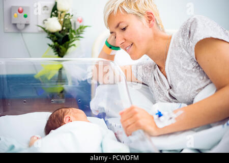 Madre mirando con amor a su bebé recién nacido niño aún en el hospital