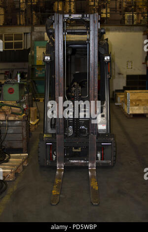 Carretilla para transportar palés en una sala de producción industrial con palets y cajas Foto de stock