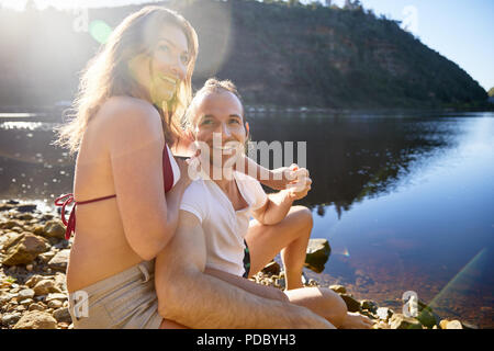Retrato afectuoso, despreocupada pareja tomados de las manos en el lago soleado de verano Foto de stock