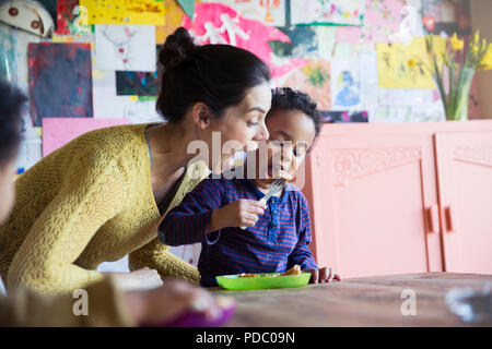 Juguetón madre e hijo desayunando waffles en la mesa Foto de stock