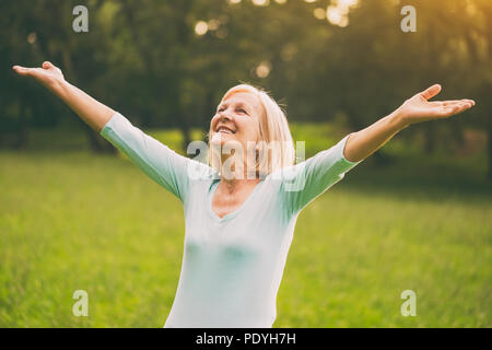 Senior mujer disfruta con sus brazos extendidos en la naturaleza.Imagen es intencionalmente tonificado. Senior mujer disfruta con sus brazos extendidos en la naturaleza.Imagen es intencionalmente tonificado.