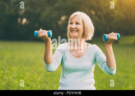 Mujer senior deportivo el ejercicio con pesas outdoor.Imagen es intencionalmente tonificado.