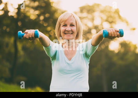 Mujer senior deportivo el ejercicio con pesas outdoor.Imagen es intencionalmente tonificado.