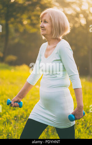 Mujer senior deportivo el ejercicio con pesas outdoor.Imagen es intencionalmente tonificado.