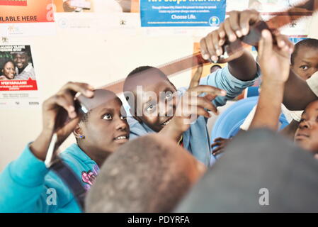 Dos jóvenes adolescentes niñas ugandeses mirar un rollo de película de 35mm durante una lección de fotografía en una escuela rural
