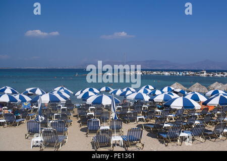 Grecia, la isla de Angistri. Filas de sombrillas decoran la playa como la temporada de verano se mete en swing Foto de stock
