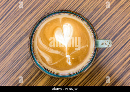 Close-up de café latte y capuchino con espuma de leche en forma de corazón en la copa como laicos plana desde arriba
