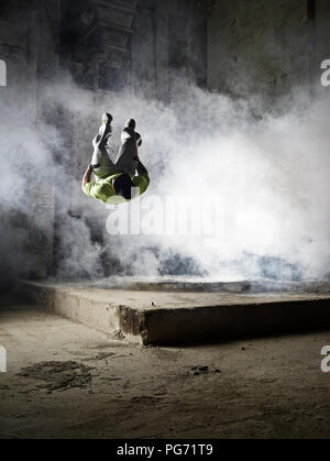 Hombre saltando en nube de polvo durante el ejercicio freerunning