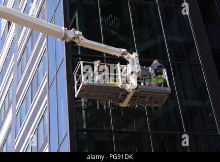 Limpieza de ventanas trabajando en un moderno edificio de cristal alto Foto de stock