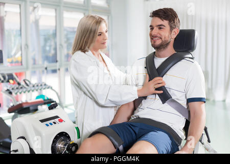 Paciente de sexo masculino en una máquina de ensayo isocinético para controlar la función de su rodilla Foto de stock