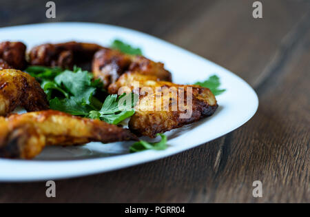 El enfoque selectivo. Caliente y picante alitas de pollo con salsa Búfalo en una placa blanca. Foto de stock
