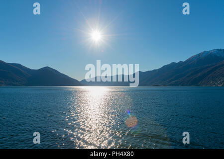 Lago Maggiore alpino con la montaña y el sol en Ascona, Suiza. Foto de stock