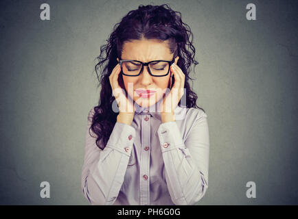 Mujer con gafas sosteniendo los dedos en las sienes intentando concentrarme en la toma de decisiones buscando destacó