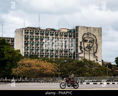 El motorista pasa Plaza Revolucion en La Habana, Cuba, donde el Ministerio del Interior, el edificio luce un mural de hierro líder guerrillero Che Guevara. Foto de stock