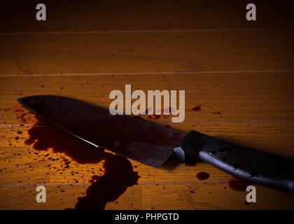 Un cuchillo dejé en el suelo empapado en sangre utilizada por un asesino o asesino. También se utiliza en el suicidio. Foto de stock