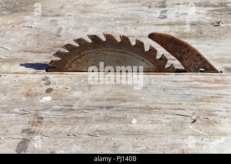 Rusty old sierra circular en un banco de madera Foto de stock