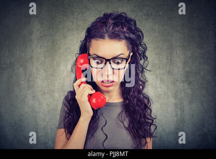 Mujer recibiendo noticias alarmantes sobre un teléfono y mirando hacia abajo con temor.