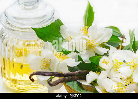 Aceite esencial con flor de jazmín y vainilla. Masaje de aromaterapia aceite  sobre fondo de madera de estilo rústico Fotografía de stock - Alamy