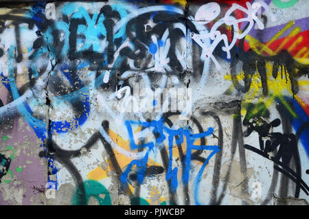  Close-up fragmento de un dibujo de graffiti aplicado a la pared con pintura en aerosol. El muro está estropeado por una multitud de coloridas firmas y marcas de Fotografía de stock -