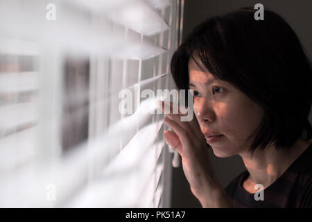 Retrato de joven mujer asiática que sobresale de la ventana