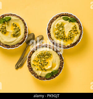 Vegan raw mini tartas de nueces y dátiles con crema de castañas de cajú del puré de mango con jugo de limón y semillas de la fruta de la pasión. alternativa saludable comida en un