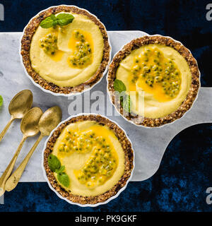 Vegan raw mini tartas de nueces y dátiles con crema de castañas de cajú del puré de mango con jugo de limón y semillas de la fruta de la pasión. alternativa saludable comida en un
