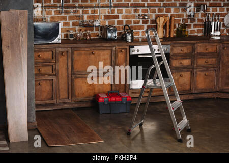 Interior de estilo loft con cocina escalera de tijera, toolbox y tablones en el piso laminado Foto de stock