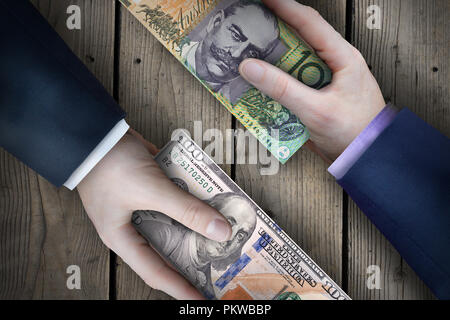 Dos billetes de moneda fiat intercambiados por dos personas de negocios como parte de una transacción de negocios. Foto de stock