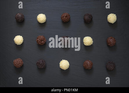 Fancy oscuro blanco leche trufas de chocolate listo para comer en piedra negra de fondo. Foto de stock