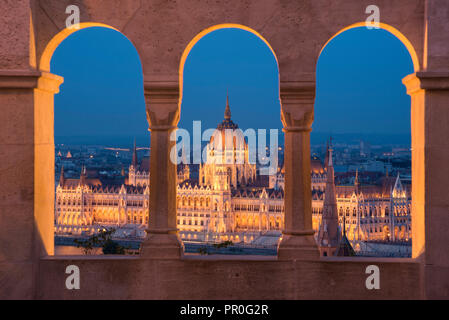 El Parlamento húngaro en la noche, visto desde las columnas y las ventanas del Bastión de los pescadores, Sitio del Patrimonio Mundial de la UNESCO, Budapest, Hungría, Europa