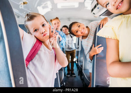 Grupo de escolares feliz viajando en autobús escolar y mirando a la cámara Foto de stock