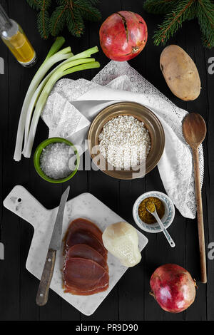 Ingredientes para el risotto receta con queso scamorza y atún ahumado de pescado. Fotografiado desde arriba, sobre un fondo de madera negra. Foto de stock