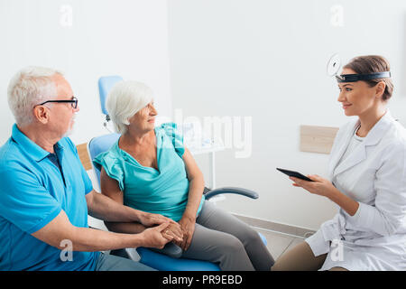 Otorrinolaringólogo hablando con altos pacientes en consultorio Foto de stock