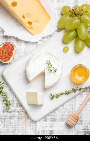 Brie o Camembert queso servido con frutas y miel sobre blanco tabla de quesos. Vista superior Foto de stock