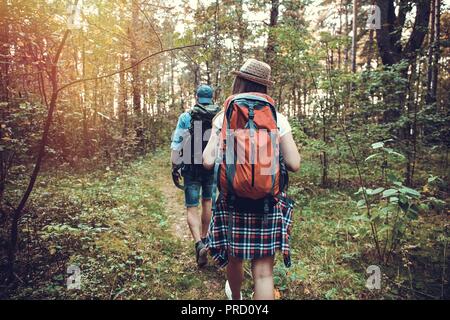 Ruta dura. Hermosa pareja joven senderismo juntos en el bosque mientras disfruta de su viaje.