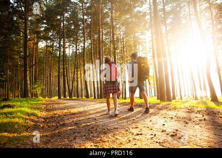 Ruta dura. Hermosa pareja joven senderismo juntos en el bosque mientras disfruta de su viaje.