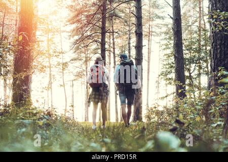 Ruta dura. Hermosa pareja joven senderismo juntos en el bosque mientras disfruta de su viaje.