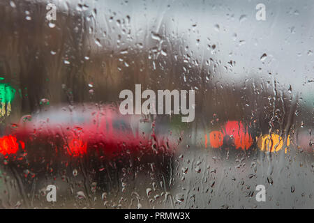 Vista de la calle a través de las gotas de lluvia en el cristal de coche Foto de stock