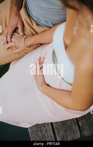 La mujer embarazada y su marido están sentados y tomados de la mano Foto de stock
