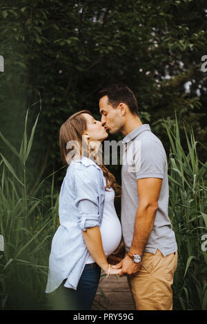 Pareja embarazada tomarse de las manos y besarse mutuamente Foto de stock
