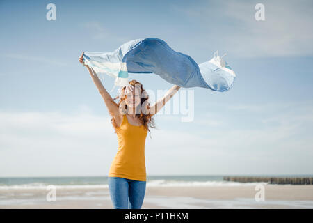 Mujer alegre y divertirse en la playa, baile y bamboleantes toalla