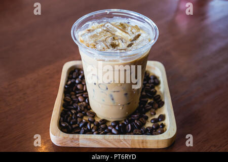 Bebida de café frío frappé o frappuccino en bandeja de madera con granos de café sobre la mesa de madera