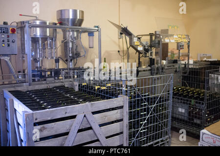 Vacío y lleno de botellas de vino embotellado fornt del equipo en una instalación de producción de vino, Apremont, Saboya, Francia. Foto de stock