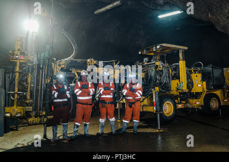 Cerro de Pasco, Perú - 13 Julio 2017: mineros dentro de la mina posando para la foto, detrás de ellos una gran máquina. Foto de stock