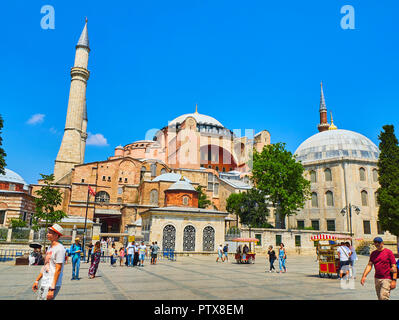 Estambul, Turquía - 10 de julio de 2018. Los turistas que caminan por delante de la Catedral de Santa Sofía Hagia Sophia, la mezquita de luz diurna y un calado de mazorcas de maíz en primer plano. Vista desde Foto de stock
