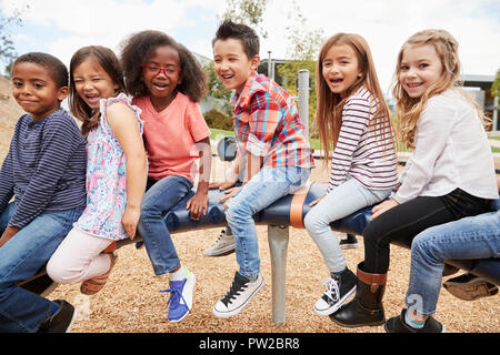 Los niños sentados en un carrusel en su patio, vista lateral Foto de stock