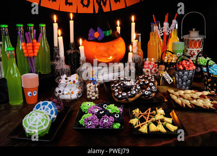 Mesa de buffet con dulces y bebidas, cocido y decorado en honor de Halloween Foto de stock