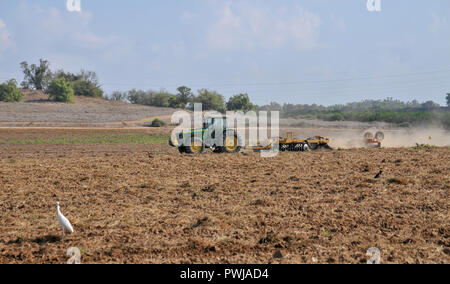 Tractor labrando la tierra en un campo agrícola fotografiado en Israel Foto de stock